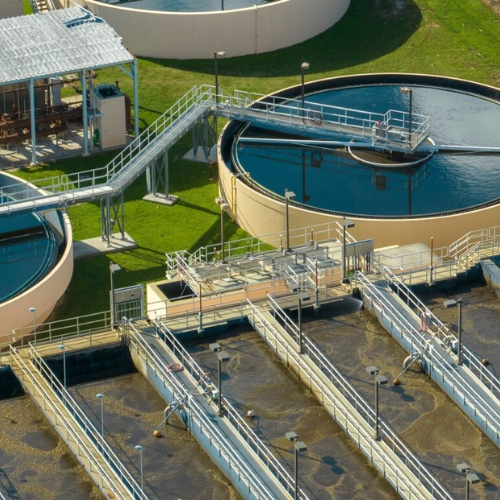 Aerial view of a wastewater treatment plant with circular clarifiers and sedimentation tanks.